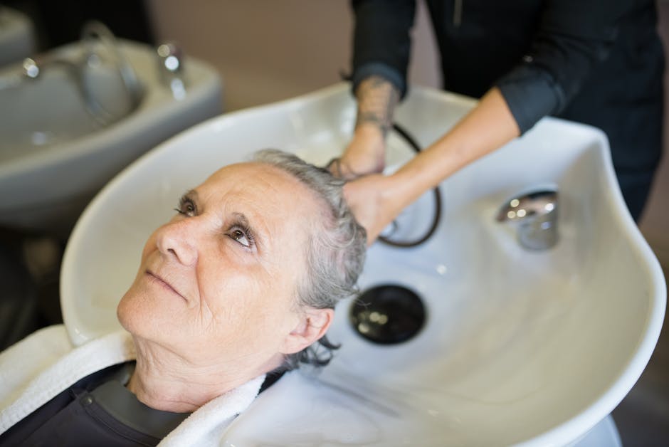Senior woman receiving a relaxing hair wash at a beauty salon with attentive service.