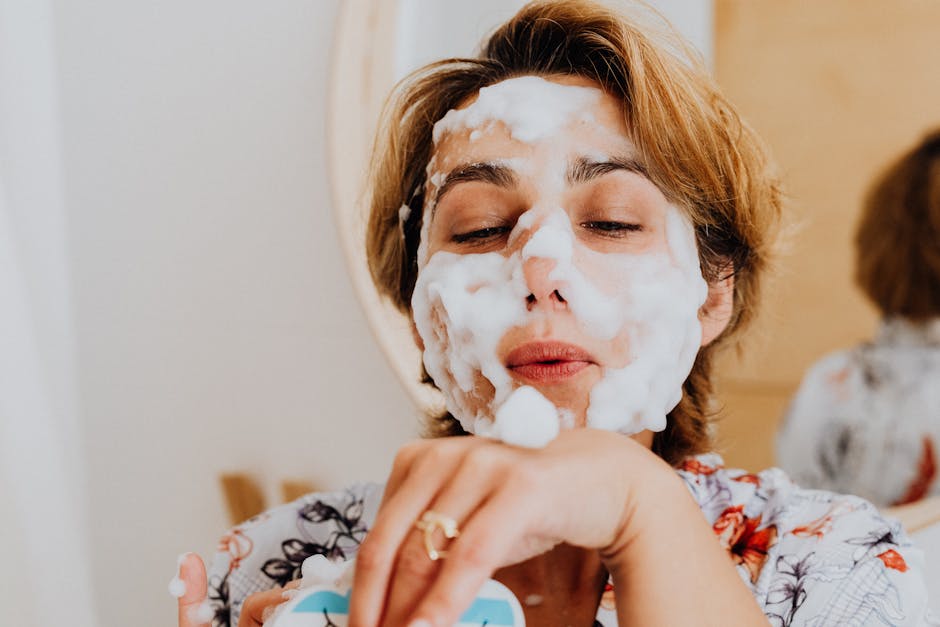 Close-up of a woman applying foamy facial wash, embracing self-care indoors.