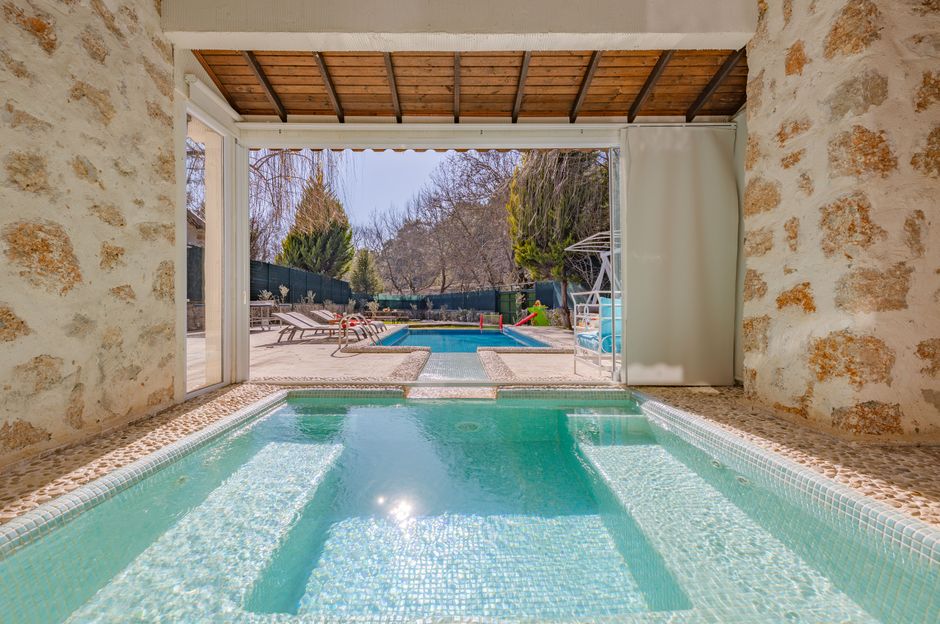 Sophisticated view of a mansion with pools and stone patio, ideal for luxury retreats.
