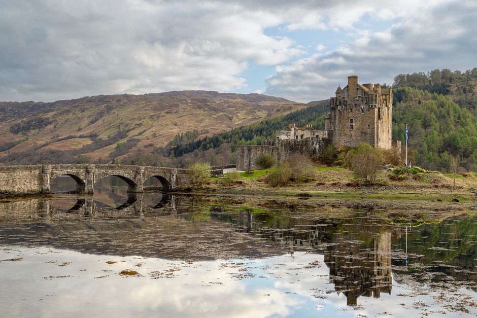 Scenic capture of Eilean Donan Castle reflecting in calm waters in Dornie, Scotland.