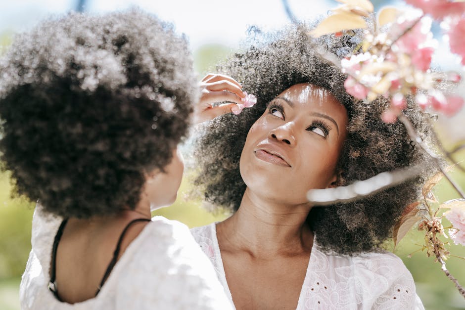 A touching moment of a mother and daughter admiring spring flowers outdoors.