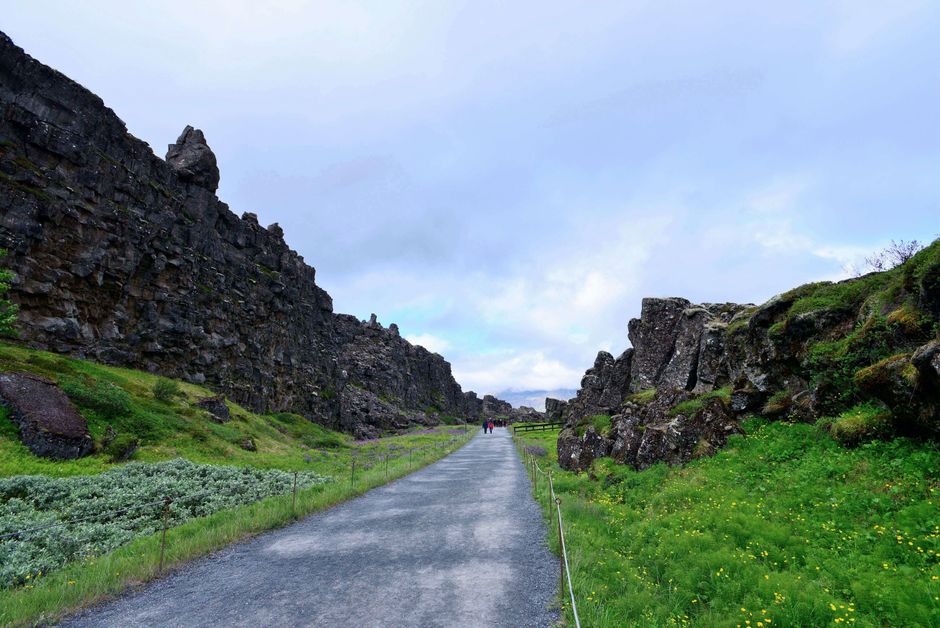 Explore a breathtaking pathway flanked by rugged cliffs in Iceland's stunning natural setting.