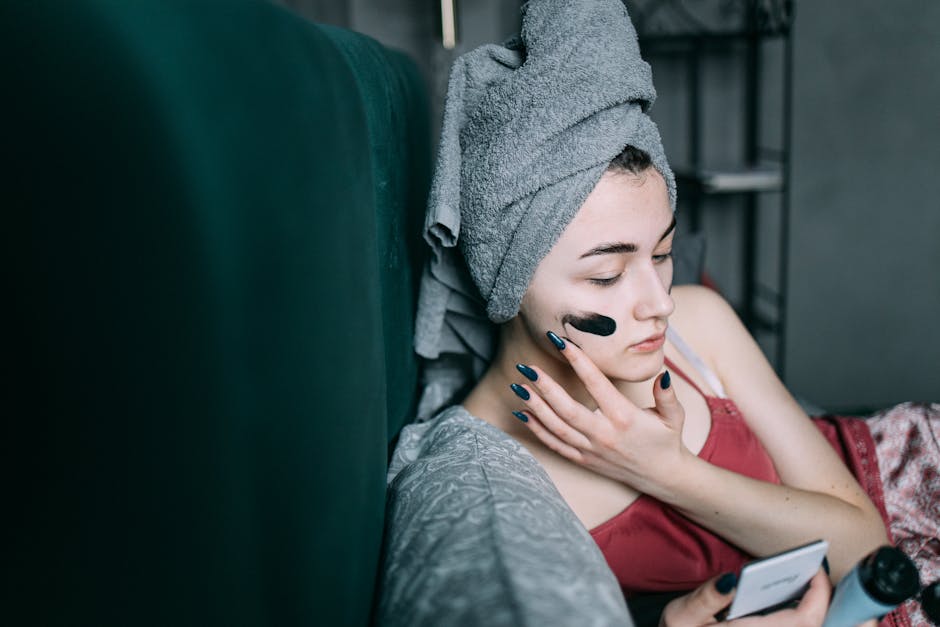 Woman at home applying a facial mask for relaxation and skincare. Self-care routine with a towel on head.