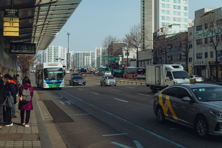 A busy street in Seoul with buses, taxis, and pedestrians in a vibrant urban setting.