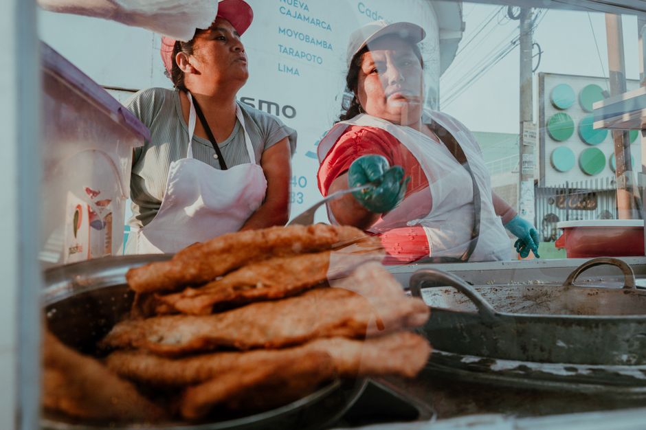 Two women selling fried food at an outdoor market stall in Pacasmayo, Peru.