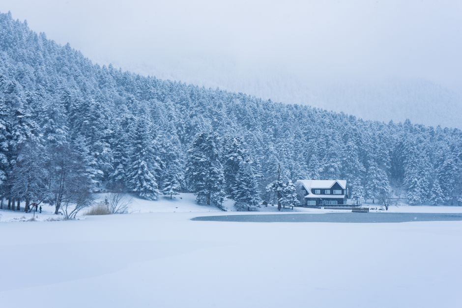 Serene winter scene of a cabin by a snowy lake in Bolu, Türkiye.