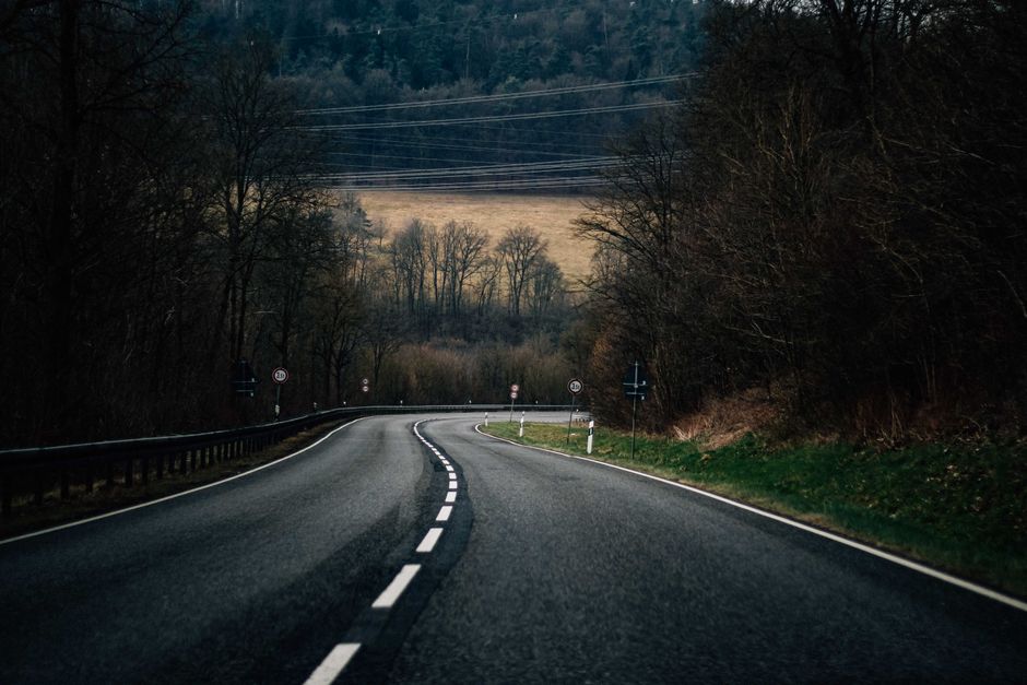 A peaceful curved road winding through an autumn forest, perfect for travel and exploration.